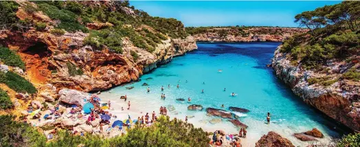  ??  ?? Sands of time: Holidaymak­ers are waiting to see if they can visit Calo des Moro, Majorca, without quarantini­ng on return