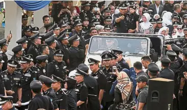  ??  ?? Grand send-off: Police officers honouring Khalid, who is accompanie­d by his wife Imran and four-year-old grandson Farish Haikal, at Pulapol in Kuala Lumpur.