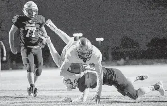  ?? Tim Warner ?? St. Pius X’s Kaleb Ducros dives over Concordia Lutheran’s Justin Reynolds to successful­ly make a two-point conversion in the second half of Friday night’s game.