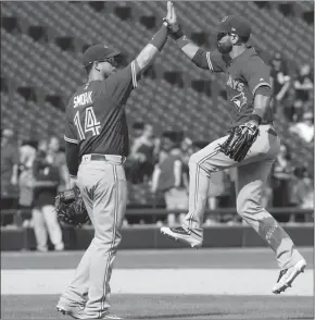  ?? The Canadian Press ?? Toronto Blue Jays right fielder Jose Bautista, right, leaps to high-five teammate Justin Smoak after defeating the Chicago White Sox 5-1 on Wednesday.