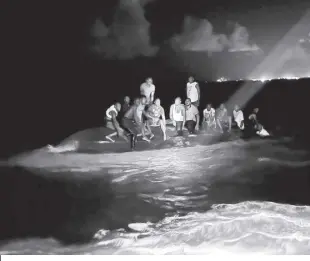  ?? ROYAL BAHAMAS DEFENSE FORCE VIA AP ?? IN this photo provided by the Royal Bahamas Defense Force, survivors sit on a capsized boat as they are about to be rescued near New Providence in the Bahamas, early Sunday, July 24, 2022. Bahamas Prime Minister Philip Brave Davis said in a statement that the dead included 15 women, one man and an infant.