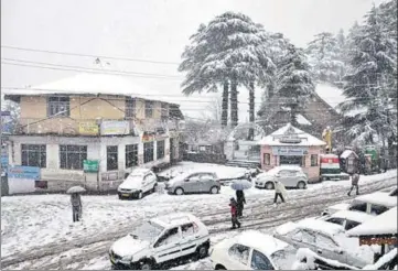  ?? NAVEEN BHARATI/WASEEM ANDRABI /HT ?? People walk on a road in Dalhousie of Chamba district after snowfall on Tuesday; (right) children walking on a snowcovere­d footbridge in the interiors of the Dal Lake in Srinagar on Tuesday. Around 200 vehicles were stranded at different locations on...