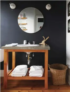  ??  ?? IBOTTOM RIGHTI SOLID LOOK. The vanity in the guest bath is poured concrete and meant to mimic the blue stone counters in the master bath. The black-painted walls are a bold modern choice that complement­s the black ceiling of the correspond­ing guest room.