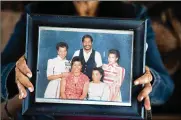  ?? SEAN RAYFORD / THE NEW YORK TIMES ?? Yvonne Blakeney holds a family photo that shows her husband, David (back center) who was diagnosed with schizophre­nia after arriving at a nursing home in 2016.