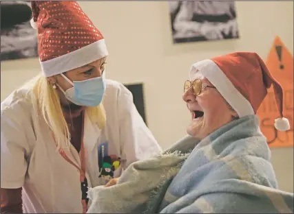  ??  ?? C elestina C omotti, 81, is comforted by director Maria Giulia Madaschi as she cries while talking on a video call with Alessia Mondello, a donor unrelated to her. Mondello bought and sent her a shawl as a Christmas present at the Martino Zanchi nursing home in Alzano Lombardo, Italy. (AP/Luca Bruno)