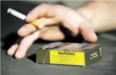  ?? DPA-BILD: VARGHESE ?? Ein Raucher hält eine brennende Zigarette in seiner Hand, die neben einer Zigaretten­schachtel liegt.