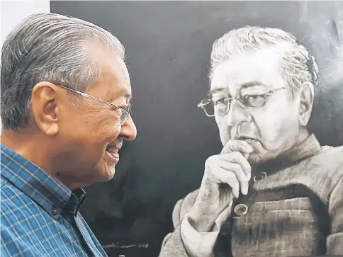  ??  ?? Dr Mahathir smiles as he looks at a portrait of himself, titled ‘Cosmologic­al Icon’ by Rahim Mat, on display at the exhibition. — Bernama photo