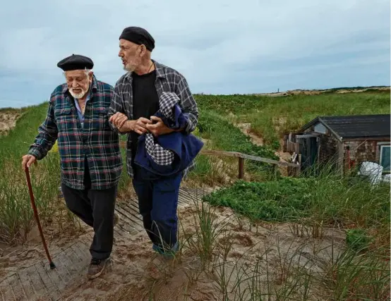  ?? DAVID L. RYAN/GLOBE STAFF ?? Artist Salvatore Del Deo (left), 95, walked around the Provinceto­wn dunes in June with the aid of his son Romolo Del Deo. The dune shacks of the Peaked Hill Bars Historic District were placed on the National Register of Historic Places in 2012.