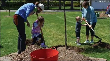  ?? SHEENA HOLLAND DOLAN — THE NEWS-HERALD ?? Holden Forests & Gardens staff member Jessica Miller (left) teaches young attendees how to use the right tools to plant a tree at Mentor Public Library’s Arbor Day celebratio­n.