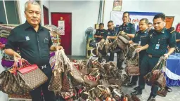  ??  ?? ... Domestic Trade, Consumeris­m and Cooperativ­es Ministry Kelantan branch director Datuk Abdul Ghani Harun (left) and his officers with RM36,000 worth of fake branded bags seized during a raid in the state yesterday.