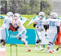  ?? AMY BETH BENNETT/SUN SENTINEL ?? Linemen Liam Eichenberg (74), Jesse Davis (77) and Robert Jones (65) run a drill during camp.