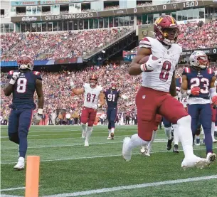  ?? CHARLES KRUPA/AP ?? Commanders running back Brian Robinson Jr. (8) scores a touchdown in front of Patriots linebacker Ja’Whaun Bentley (8) and safety Kyle Dugger (23) in the first half Sunday.