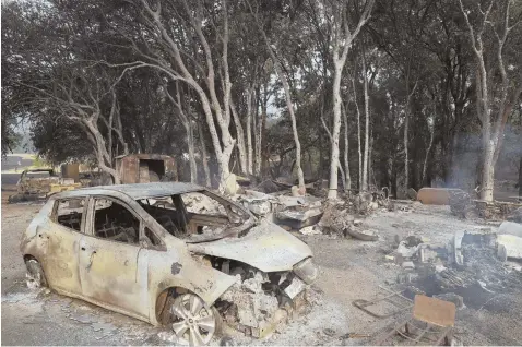  ?? AP PHOTOS ?? DAMAGE: A burned car is seen in front of a wildfire ravaged home yesterday in Lakeport, Calif. An air tanker, below passes behind a smoke plume while battling the River Fire in Lakeport.