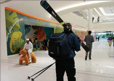  ?? (AP) ?? A man carries skis and poles after visiting “The Big Snow” ski slope inside American Dream mall in East Rutherford, N.J., in October. The mall reopened in October after it abruptly closed in March because of the pandemic.