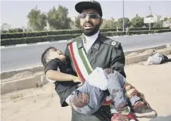  ??  ?? 0 A Revolution­ary Guard member carries a wounded boy