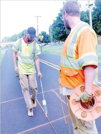  ?? LYNN KUTTER ENTERPRISE-LEADER ?? Chris Brisher, left, and Jake Fleetwood with Time Striping of Van Buren prepare to stripe pedestrian walkways on Rheas Mill Road between the high school campus and Ledbetter Intermedia­te.