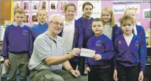  ??  ?? Members of Ballachuli­sh Primary School Pupil Council, left to right, Arron Callender, Ethan Starkey, Cali Donald, Ellie Chisholm, Ava Bathurst, Lucy MacMillan and Ema MacInnes, with Shay Lynsay presenting the cheque to Iain Ferguson.