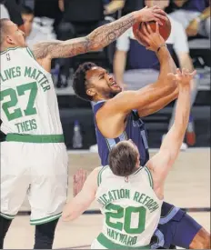  ?? Mike Ehrmann / Getty Images ?? The Grizzlies’ Kyle Anderson, center, tries to shoot the ball as the Celtics’ Daniel Theis, left, and Gordon Hayward defend.