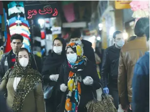  ?? (WANA/Reuters) ?? IRANIANS WEAR protective face masks and gloves as they walk in Tehran’s Tajrish market ahead of Friday’s Nowruz New Year festival.