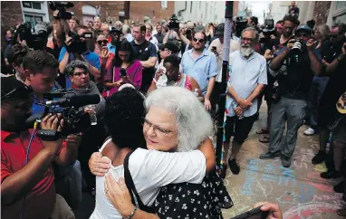  ?? WIN MCNAMEE/GETTY IMAGES ?? Susan Bro hugs a young woman near a memorial for her daughter Heather Heyer, who was killed during last year’s protests in Charlottes­ville, Va. Bro also acknowledg­ed the others who were injured that day.
