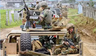  ?? (Mindanao Examiner Photo) ?? U.S. troops pass a dirt road in Jolo town on their way to a remote village in the town of Panamao in this picture taken in September 2006 in Sulu province in the southern Philippine­s. The U.S. forces are assisting and advising the Philippine military on the war against terrorism.