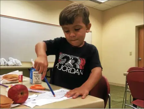  ?? ZACH SRNIS — THE MORNING JOURNAL ?? Isaiah Serrano, 4, of Lorain, works on his dragon flyer during the library’s free lunch event.