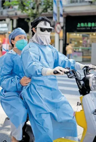  ?? REUTERS ?? Dos personas con indumentar­ia de protección frente al Covid en Shanghái.