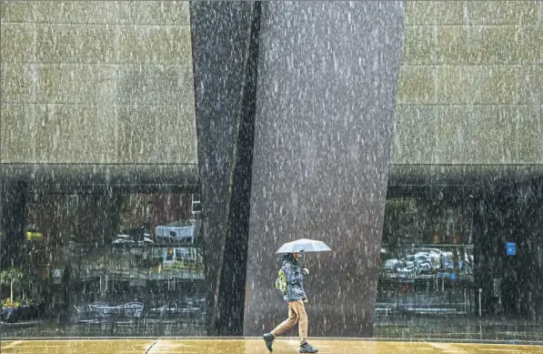  ?? Andrew Rush/Post-Gazette ?? Heavy rain falls Monday as a pedestrian walks in front of the Carnegie Museum of Art in Oakland.