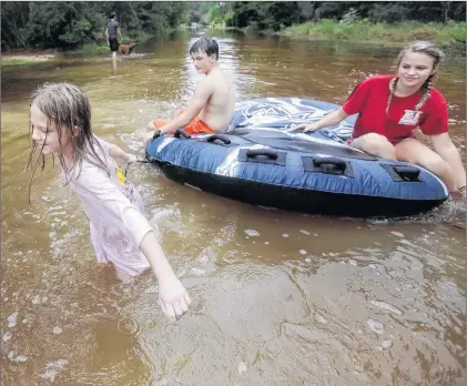  ?? AP PHOTO ?? Crimson Peters, 7, from left, Tracy Neilsen, 13, and Macee Nelson, 15, ride in an inner tube down a flooded street after hurricane Nate on Sunday in Coden, Alabama.