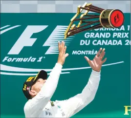  ?? CP PHOTO ?? Lewis Hamilton of Great Britain tosses the winner’s trophy after winning the Canadian Grand Prix yesterday in Montreal.