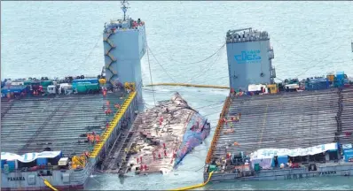  ?? PARK GYUNG-WOO / ASSOCIATED PRESS ?? Workers prepare to lift the Sewol ferry in the waters off Jindo Island in South Korea on Thursday. The 6,800-ton vessel capsized and sank in April 2014, claiming the lives of 304 people, mostly school students on a trip.