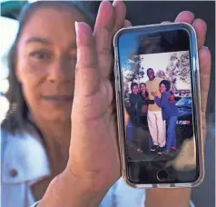  ?? PHOTOS BY ROBERT HANASHIRO/USA TODAY ?? Toney Carson shows a picture of her and other locals at the Ladera Starbucks with Lakers star Earvin “Magic” Johnson when it opened.