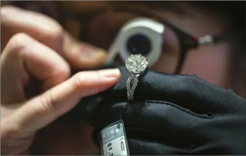  ?? BILLY H.C. KWOK / BLOOMBERG ?? An employee inspects a diamond ring at a Chow Tai Fook Jewellery Group Ltd store in the Central. The spread of synthetic diamonds, also known as lab-grown diamonds, is posing a threat to the viability of real gems in the global diamond market.