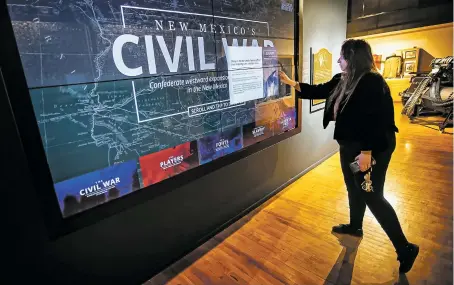  ?? JIM WEBER/THE NEW MEXICAN ?? Laureta Huit, collection­s manager at the New Mexico Military Museum, shows off the museum’s ‘New Mexico’s Civil War’ interactiv­e exhibit last week. The giant screen can call up all kinds of informatio­n about the places, players, politics and battle plans of the struggle to take New Mexico in the early days of the Civil War.