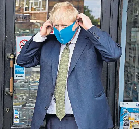  ??  ?? The Prime Minister sports a £2 Poundstret­cher face mask in his Uxbridge constituen­cy following days of criticism that senior ministers and opposition figures were not wearing them