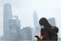  ?? AP Photo/Andy Wong ?? A woman wearing a mask walks to a subway station during the evening rush hour Feb. 21 in Beijing.