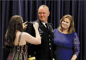  ?? Arkansas Democrat-Gazette/THOMAS METTHE ?? Arkansas National Guard Brig Gen. Bradley Cox’s daughter Jordan (left) and wife, Melissa, (right) put epaulets signaling his new rank on his uniform Saturday during his promotion ceremony at Camp Robinson in North Little Rock. More photos are available at www.arkansason­line.com/714promo/