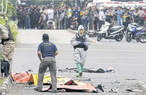  ?? Members of the Indonesian police stand near dead victims after a bomb blast in front of a shopping mall yesterday. Police exchanged fire with suspected attackers at a traffic police post facing the Sarinah shopping centre and a nearby Starbucks coffee sho ??