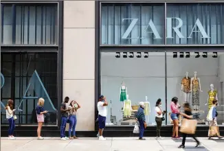  ?? SHAFKAT ANOWAR/AP 2021 ?? Shoppers wait outside a Chicago downtown retail store in May. Fueled by vaccinatio­ns and government aid, the U.S. economy grew at a solid 6.6% annual rate last quarter.