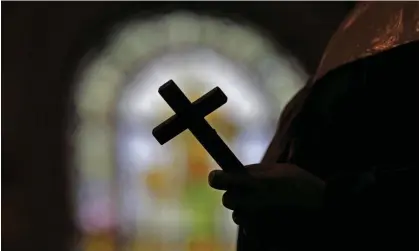  ?? Photograph: Gerald Herbert/AP ?? This 2012 file photo shows a silhouette of a crucifix and a stained glass window inside a Catholic church in New Orleans.