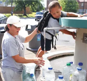  ??  ?? Tyson Haywood, 3, right, assists his grandmothe­r, Annette Loy, in filling water bottles at the Hill Wheatley Plaza Thermal Water Station in 2011. she said they use it for a variety of things including drinking and replenishi­ng the fish tank.