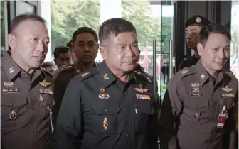  ??  ?? A file photo of Thai Army Lieutenant-General Manas Kongpan (C) being surrounded by police officers as he turns himself in at the police headquarte­rs in Bangkok —