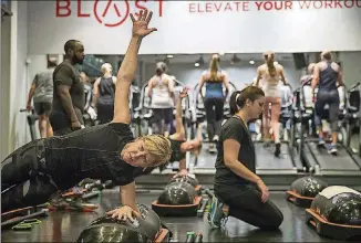  ?? ALYSSA POINTER/ALYSSA.POINTER@AJC.COM ?? Leslie Wilson (left) completes a side plank during a Blast full body workout at the flagship Blast Buckhead studio.