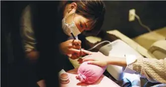  ??  ?? A stylist manicures nails of a Japanese customer at a nail salon in Tokyo.