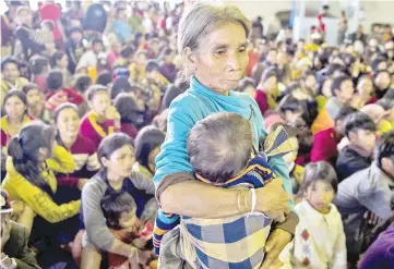  ??  ?? An elderly woman carries a child while other residents displaced by massive flood waters from the collapsed dam seek shelter in Paksong town in Champasak province.