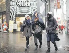  ??  ?? Tourists walk in the Myeongdong shopping district during snowfall in Seoul, South Korea. South Korea’s central bank kept its key interest rate unchanged at a record low 1.5 per cent for an eighth straight month yesterday, with the local currency...