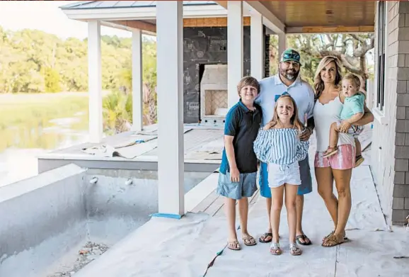  ?? HUNTER MCRAE/THE NEW YORK TIMES ?? Todd and Heather Wigfield with their children at the constructi­on site for their new home on July 16 in Mount Pleasant, South Carolina.