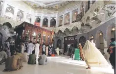  ?? — Reuters photo ?? A woman clad in burqa walks in the hallway of the tomb of Sufi saint Syed Usman Marwandi, also known as Lal Shahbaz Qalandar in this file picture.