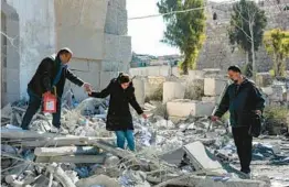  ?? LOUAI BESHARA/GETTY-AFP ?? A woman is helped as she walks through rubble in the aftermath of a reported Israeli airstrike Sunday in Damascus, Syria, that caused at least five deaths.