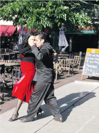  ?? CELESTE MOURE/FOR POSTMEDIA NEWS ?? A couple dances the tango beside one of the endless cafés that line the streets of Buenos Aires.